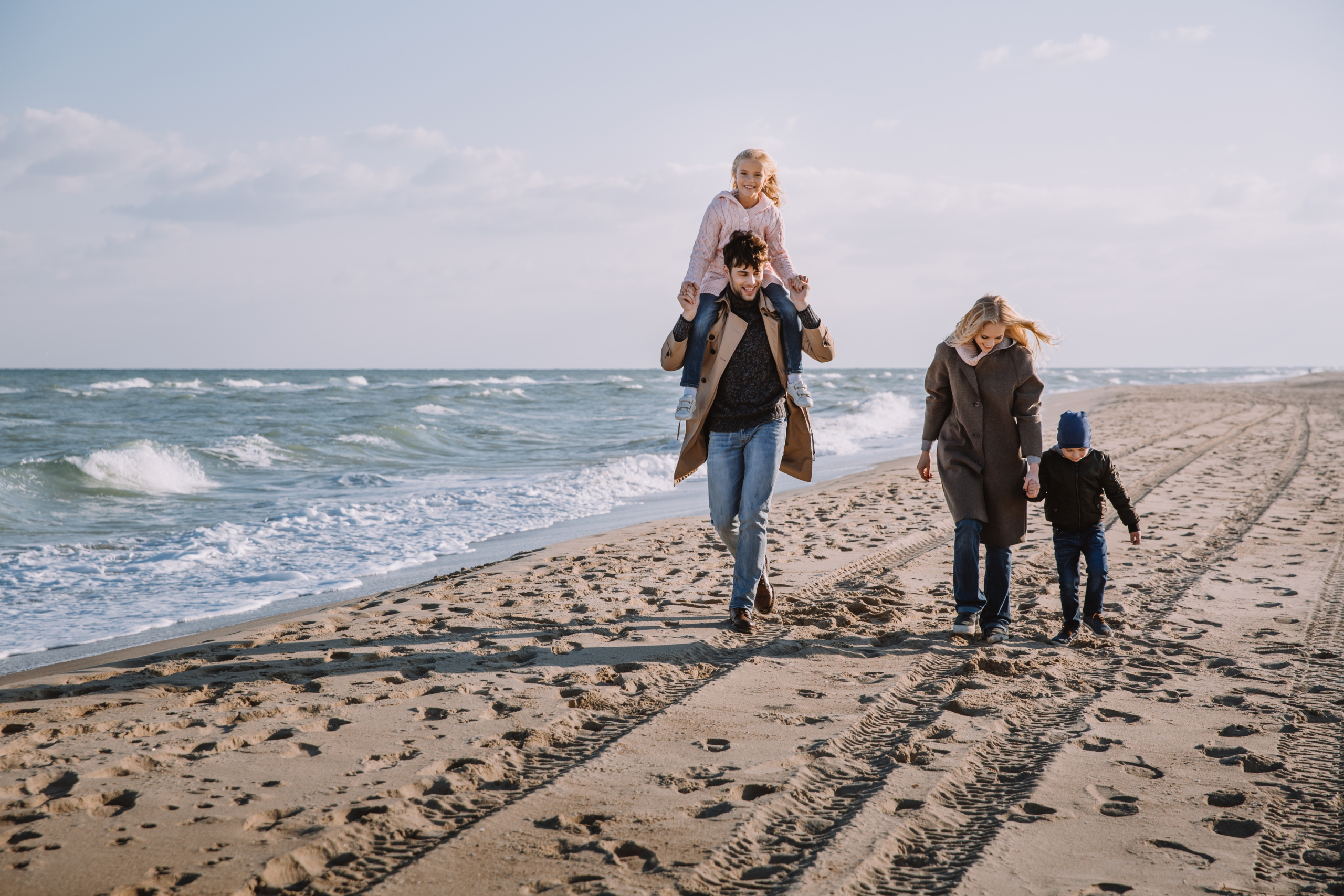 happy family walking together on seashore in autumn
